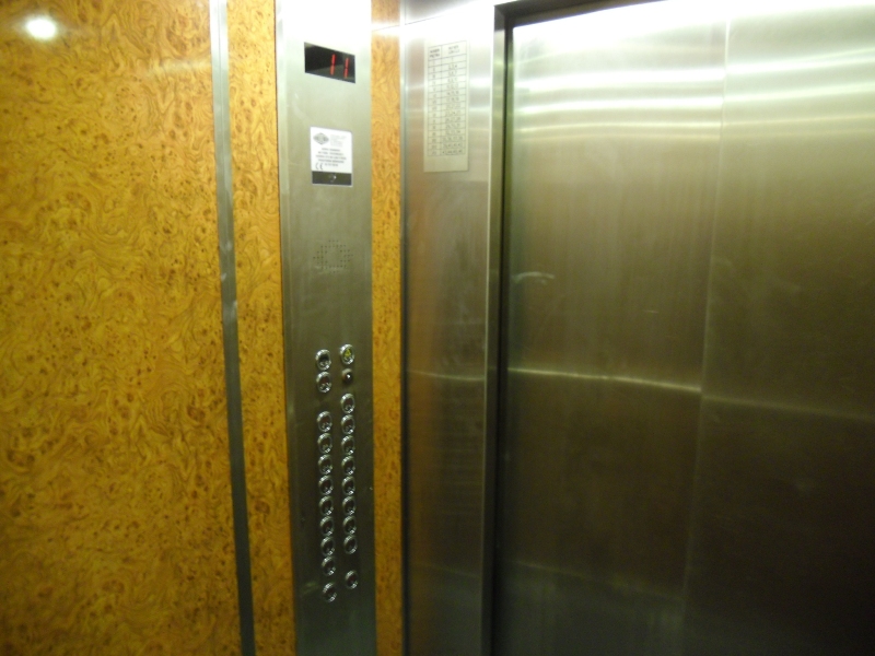 Winda z grawerowaną tabliczką pięter i numerów mieszkań przypominającą PKiN